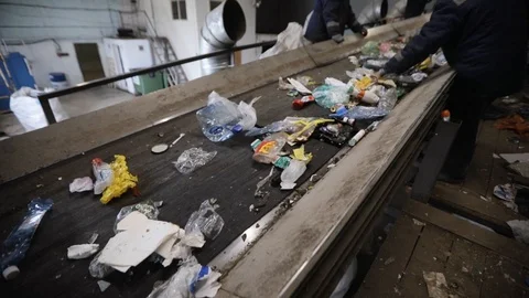 Workers sorting waste on moving conveyor belt at recycling plant for reuse. Stock Footage 120123583