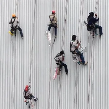 Workers on the Strings  are Cleaning Windows of the skyscraper Stock Photos