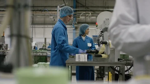 Workers talking to each other while labeling cosmetic boxes in factory Stock Footage 107959838