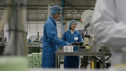 Workers talking to each other while labeling cosmetic boxes in factory Stock Footage 107960050