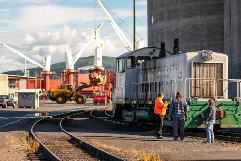 Workers talking on pier while machinery operates in the background Stock Photos