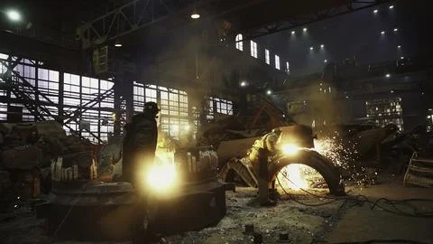 Workers toiling diligently in a Steel Mill surrounded by molten metal and an Stock Photos