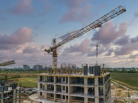 Workers on the top of the building with cranes. Stock Photos
