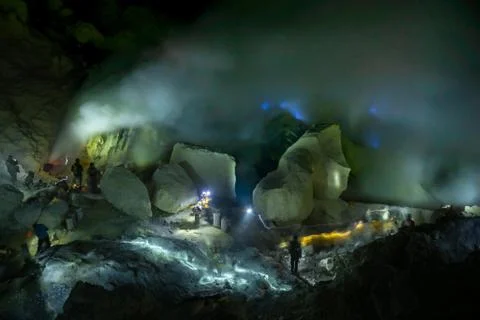 Workers in toxic sulfur mining in sulfur mine at night back blue fire of Photos