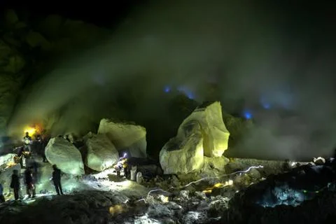 Workers in toxic sulfur mining in sulfur mine at night back blue fire of Fotos de archivo