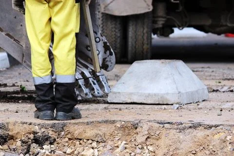 Workers trying to load a concrete stand on road sign in the excavator buck... Stock Photos