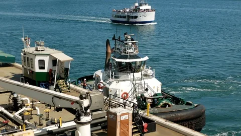 Workers in a tugboat along side of a barge boat and a tour boat as a background Stock-Footage 122010694