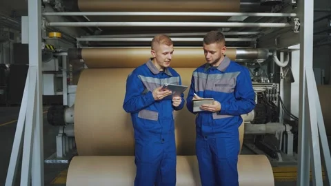 Workers in uniform at the factory stand next to the operating production line, a Stock Footage 280789932