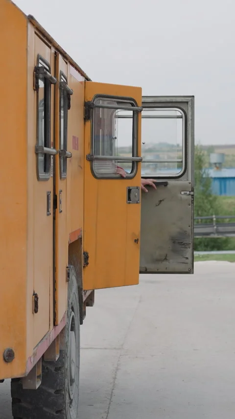 Workers in uniform get in big orange vehicle closing doors Stock Footage 309049929