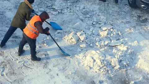 Workers in uniform on a winter day shovel snow, a tractor with a scraper bucket Stock Footage 168932268