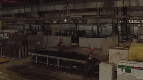 Workers unload metal sheet onto workstation in busy factory Stock Footage 329015062