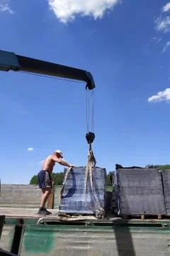 Workers unload pallets with bricks by means of the crane of automobile. Stock Photos