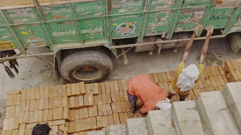 Workers unloading and stacking red clay bricks at construction site, hyderabad Stock Footage 319822945