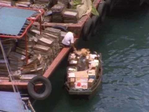 Workers unloading boxes on small boat in harbor Stock Footage 79879005