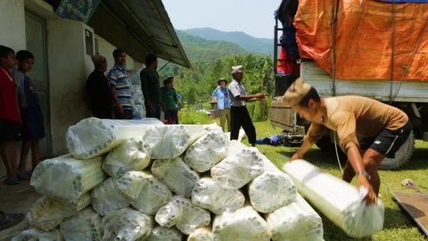 Workers unloading bundles of pipes from a truck and piling them on the ground Stock Footage 77444325