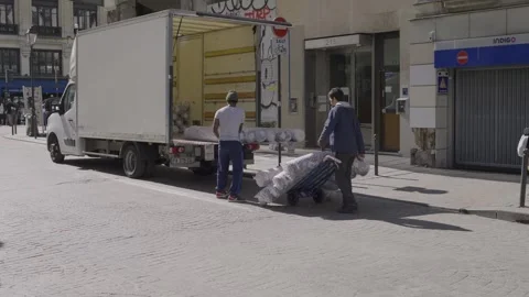 Workers unloading large cargo from truck in busy street of Paris, manual labor Stock Footage 305755188