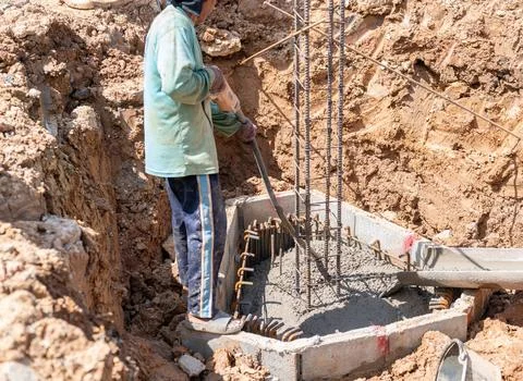 Workers use a concrete vibrator to compact the concrete and eliminate voids. Stock-Fotos