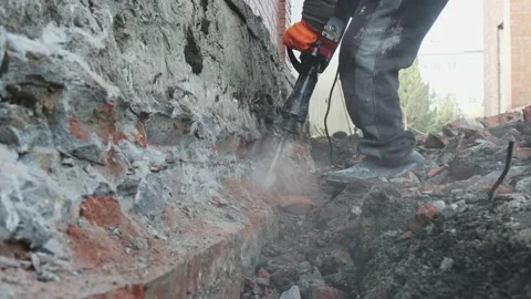 Workers use an electric jackhammer to break off an old foundation. Stock Footage 233617319