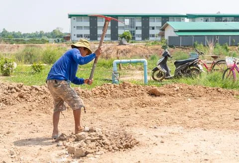 Workers use pickaxe digging the soil surface to level it. Stock Photos
