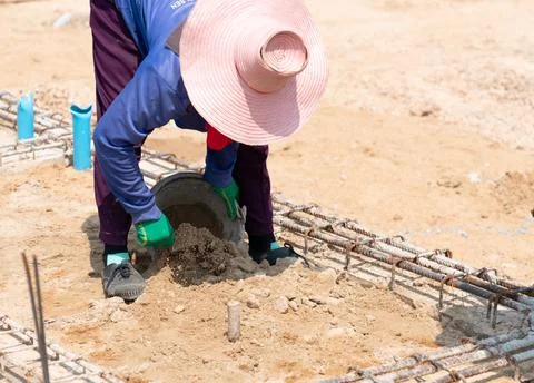 Workers use plastering trowel to dig out excess sand from the ground . Stock Photos