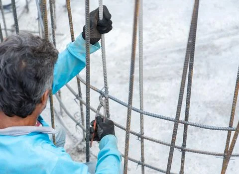 Workers use pliers to tie wire to rebar. Stock Photos