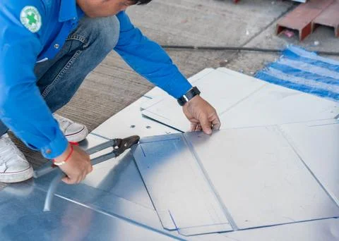 Workers use scissors to cut the metal sheet. Stock Photos