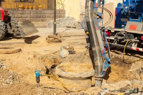 Workers use a suction excavator based on a truck to sample soil in a well for Stock Photos