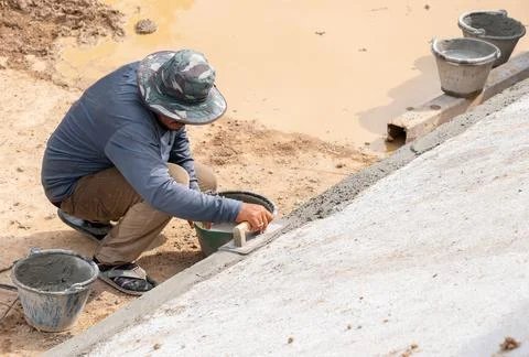 Workers use trowel plastering on the edge of the pool. Stock Photos