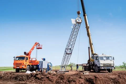 Workers using construction equipment install wind turbine tower Stock Photos
