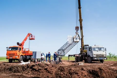 Workers using construction equipment install a wind turbine tower Stock Photos