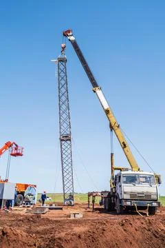 Workers using construction equipment install a wind turbine tower Stock Photos