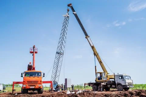 Workers using construction equipment install a wind turbine tower Stock Photos