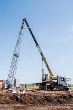 Workers using construction equipment install a wind turbine tower Stock Photos