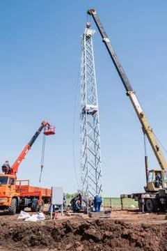 Workers using construction equipment install a wind turbine tower Stock Photos