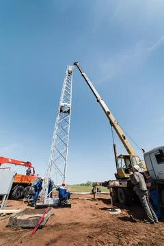 Workers using construction equipment install a wind turbine tower Stock Photos