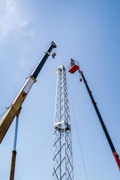 Workers using construction equipment install wind turbine tower Stock Photos