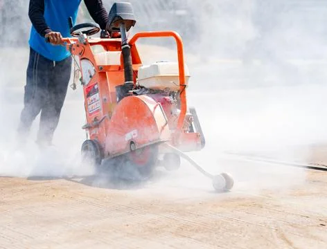 Workers using cutting machine are cutting concrete for joint of slab on road. Foto stock