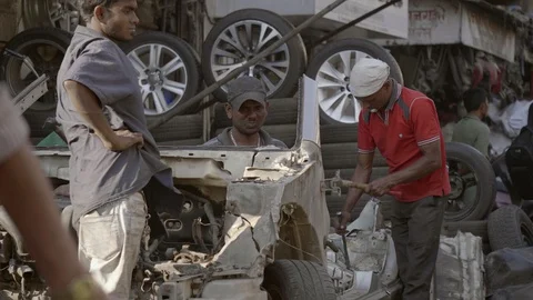 A workers using hammer to dismantle an old car in automobile chor Bazaar Stock Footage 128732710