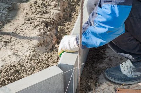 Workers using machine to align and set the concrete curbs. Concrete kerb inst Stock Photos