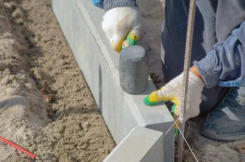 Workers using machine to align and set the concrete curbs. Concrete kerb inst Stock Photos