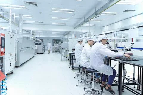 Workers using microscopes in factory that specialises in creating functional Stock Photos