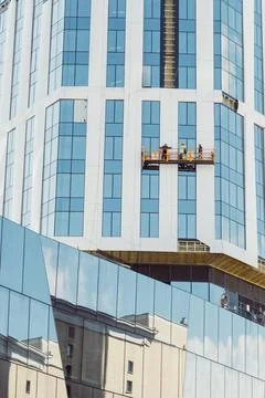 Workers using specialized equipment to access and clean windows of skyscraper. Stock Photos