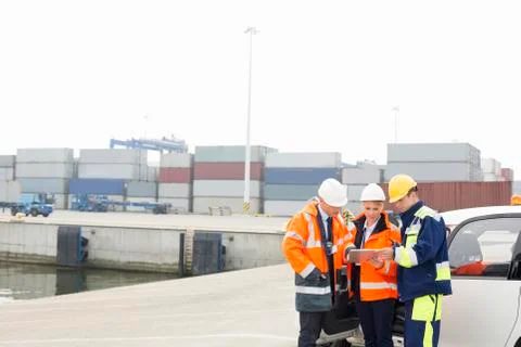 Workers using tablet PC beside car in shipping yard Stock Photos