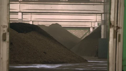 Workers walk among large ore mounds in storage of plant Stock Footage 104018559