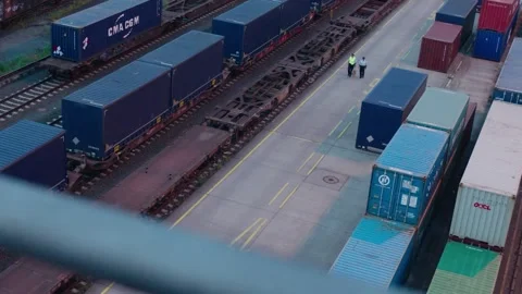 Workers Walking Between Shipping Containers in Rail Yard from Overhead Angle Stock Footage 334583043