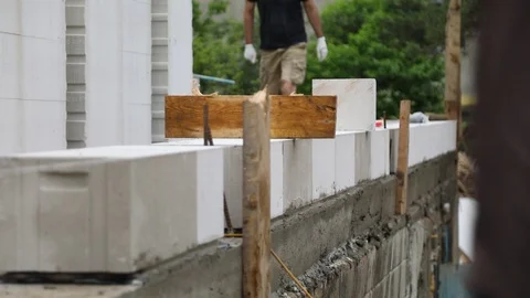 Workers walking in front of the prepared line of the aerated concrete blocks Stock-Footage 103126648
