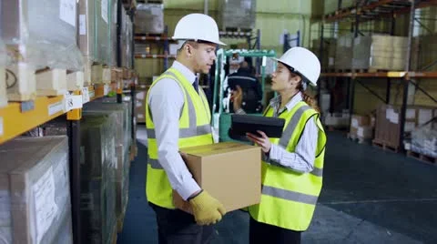 Workers in a warehouse with a digital tablet are discussing their work. Stock Footage 13474008