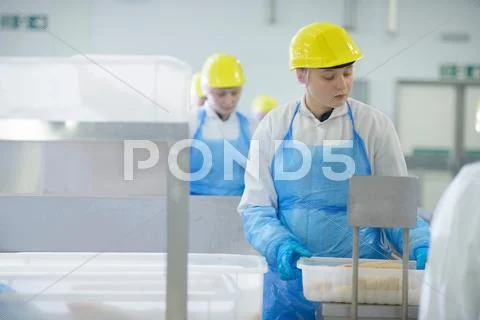 Workers Wearing Hard Hats On Production Line In Food Factory