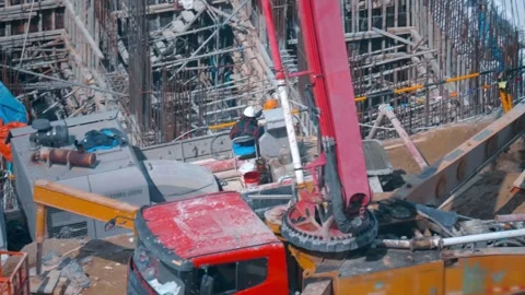 Workers wearing protective gear, heavy machinery, including a concrete pump boom Stock Footage 340632262