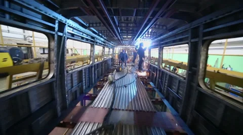 Workers weld inside dark train coach at workshop in factory Stock Footage 32235096